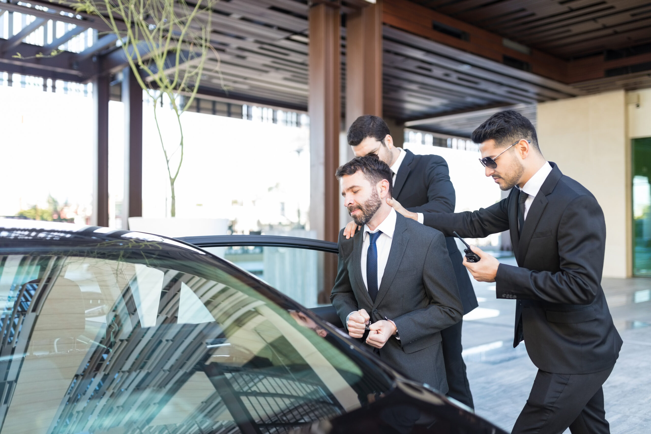 Young undercover agents pushing businessman towards car in financial fraud case