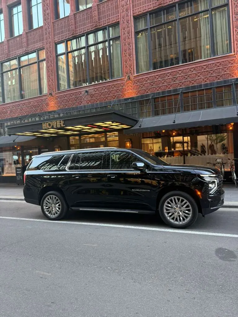 Black luxury SUV parked outside a historic hotel building.